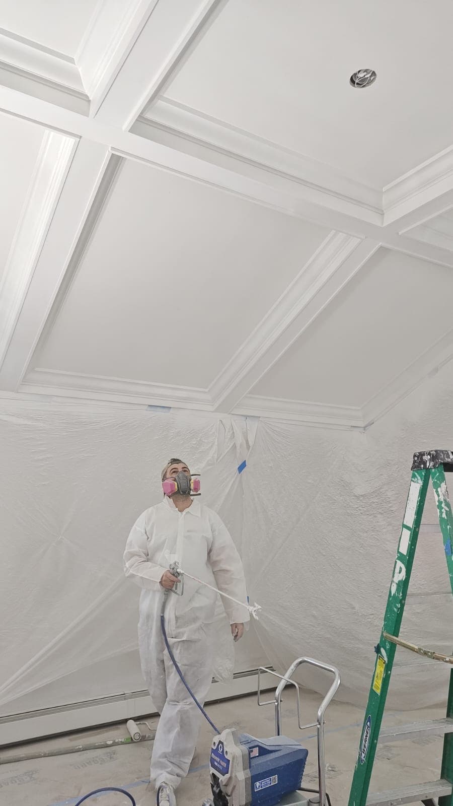 LV Painting professional spraying a coffered ceiling with full protective masking